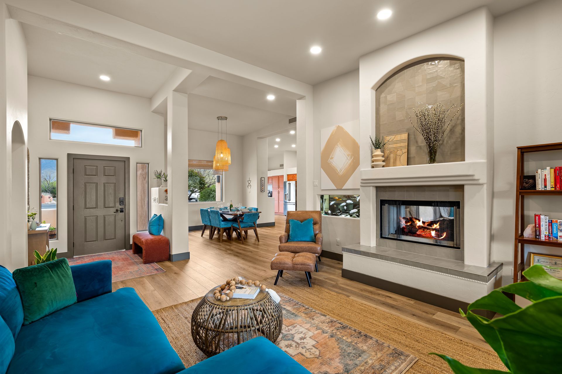 Living room with teal sofa, fireplace, and open dining area.