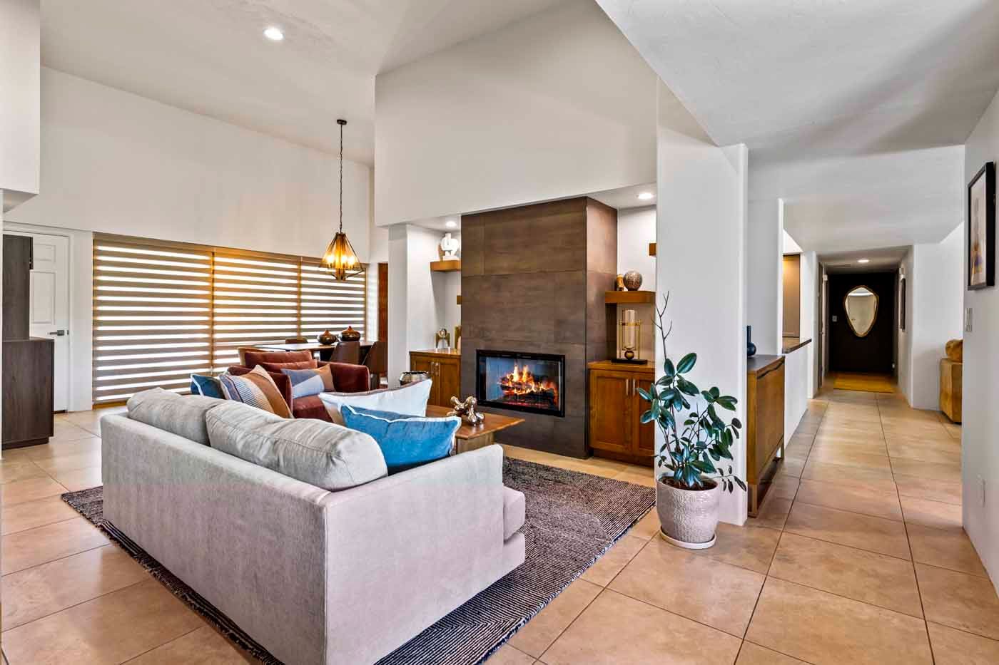 Cozy living room with fireplace, sofa, dining area, and large windows with blinds.