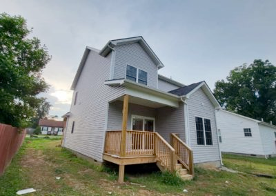 The back of a house with a wooden deck and stairs.