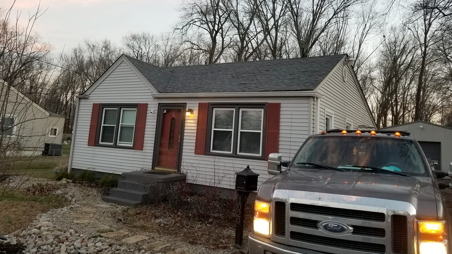 A truck is parked in front of a small white house.