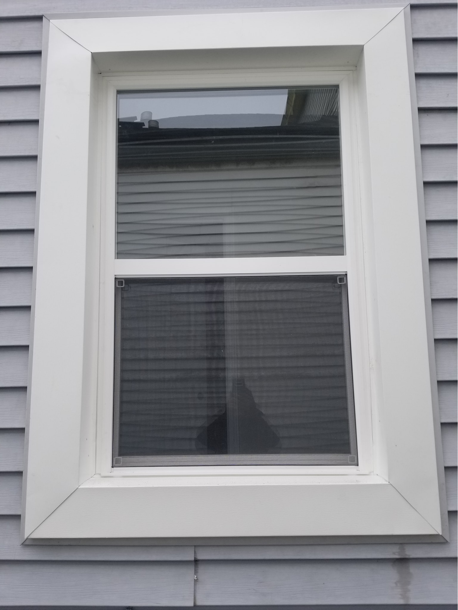 A white window is on the side of a house.