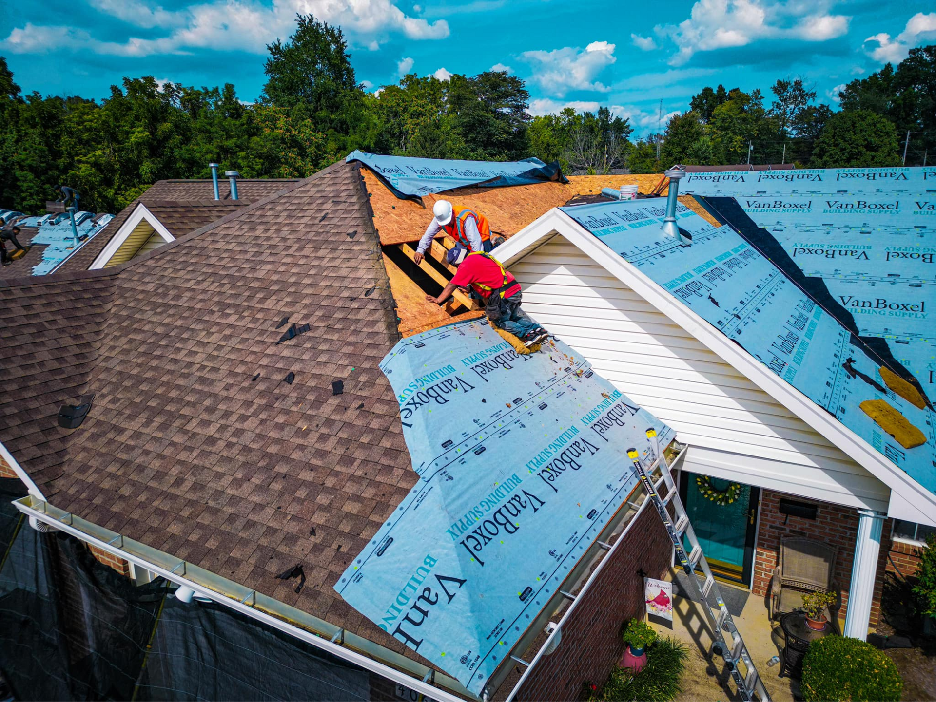 A couple of men are working on the roof of a house.