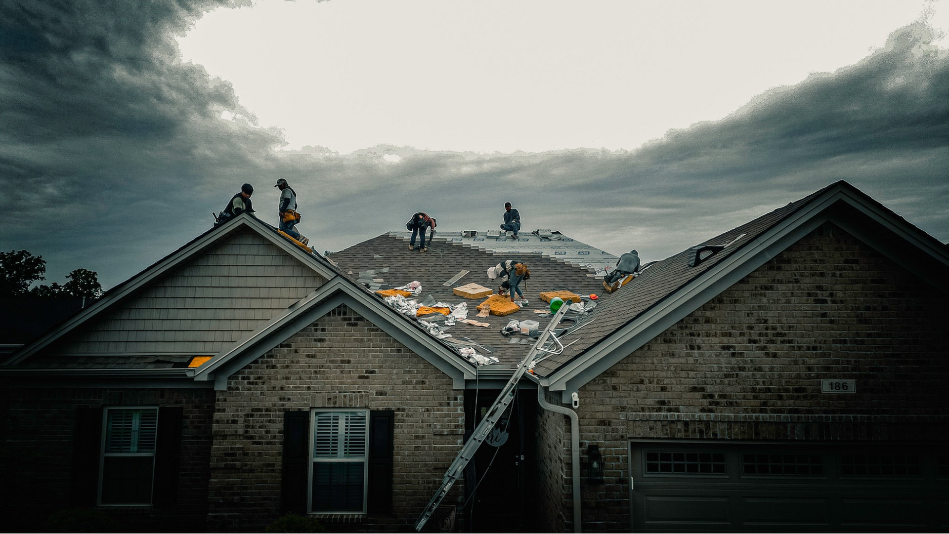 A group of people are working on the roof of a house.
