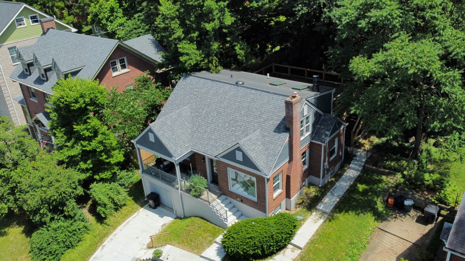 An aerial view of a house in a residential area surrounded by trees.