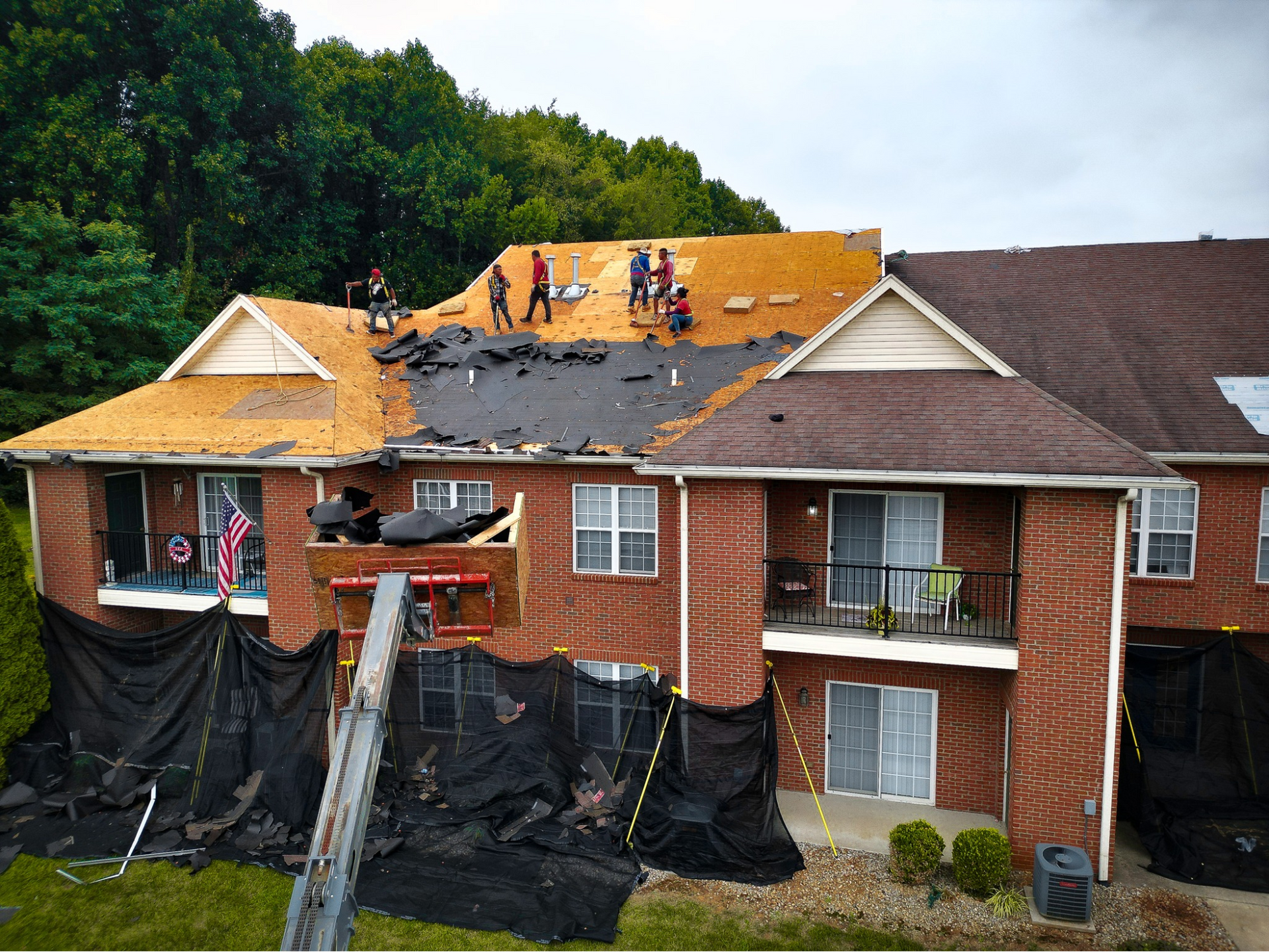 A group of people are working on the roof of a brick apartment building.