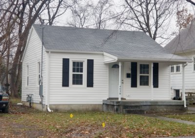 A small white house with black shutters on the windows