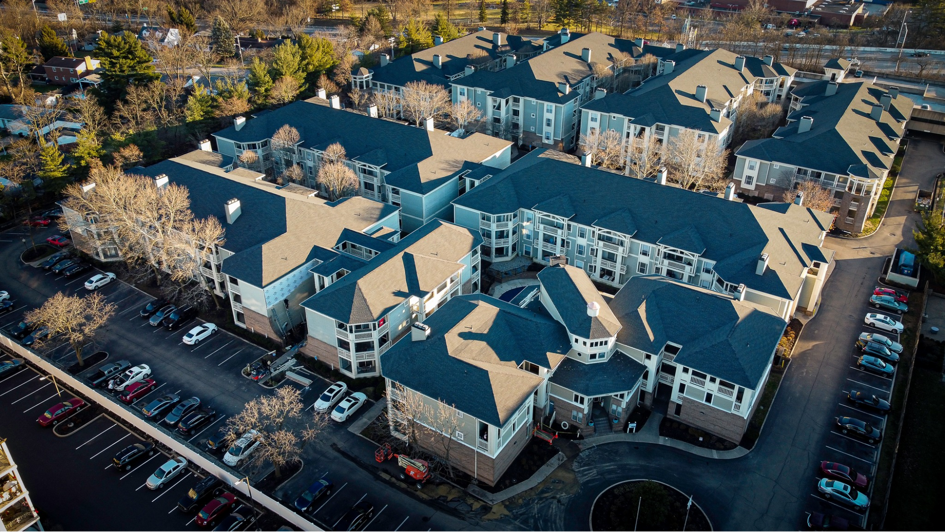 An aerial view of a large apartment complex with lots of cars parked in front of it.