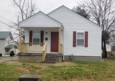 A small white house with red shutters and a porch.