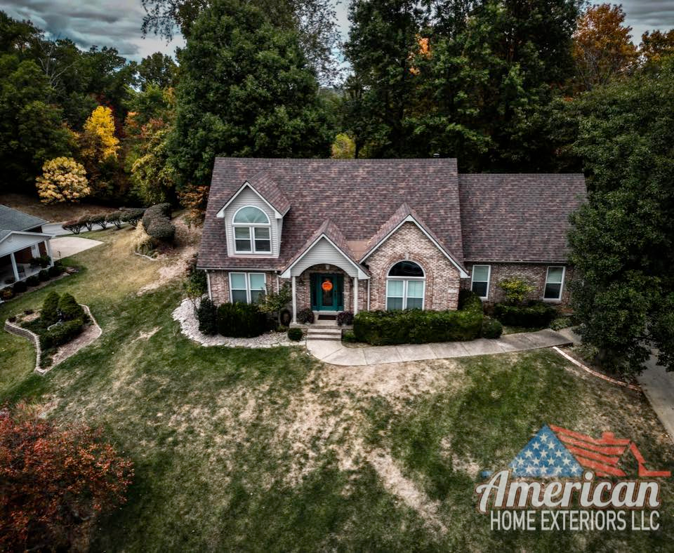 An aerial view of a large brick house surrounded by trees.