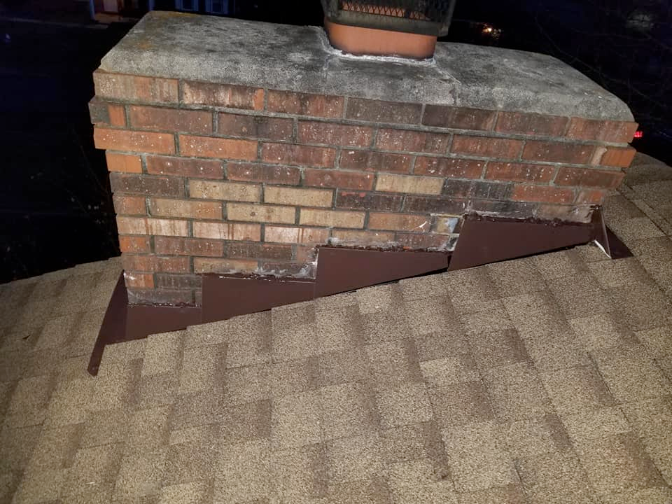 A brick chimney is sitting on top of a roof.