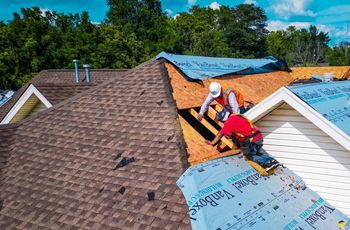 two men are working on a roof of a house .