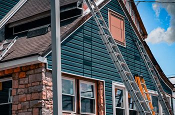 a man on a ladder is working on the side of a house .