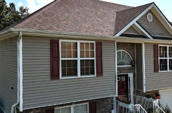 a house with a roof , siding , windows and shutters .