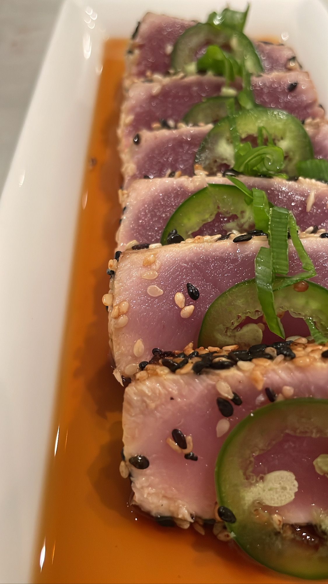 Seared Yellowfin Tuna appetizer topped with compressed jalapeno and finished with chili oil