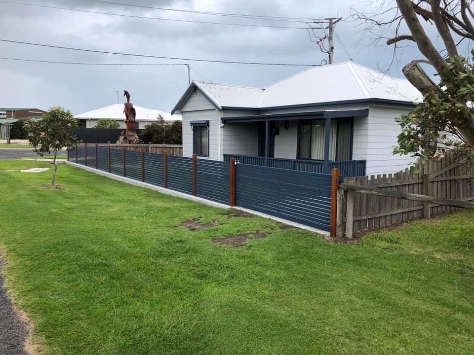 A white house with a blue fence in front of it.