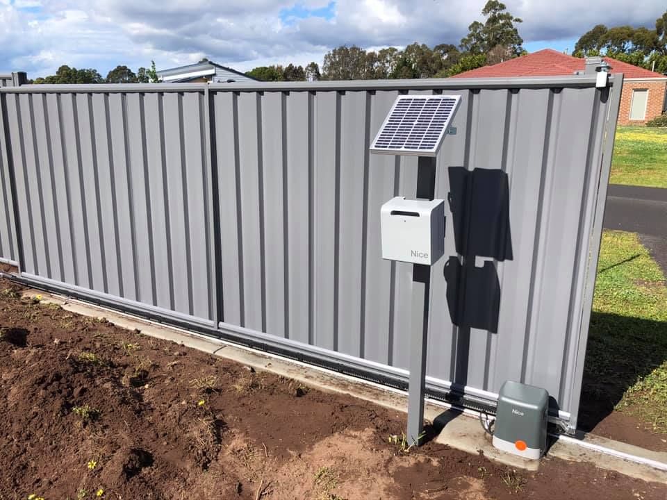 A fence with a solar panel and a mailbox on it.