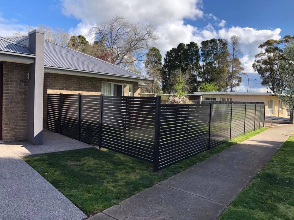 A brick house with a black fence in front of it.