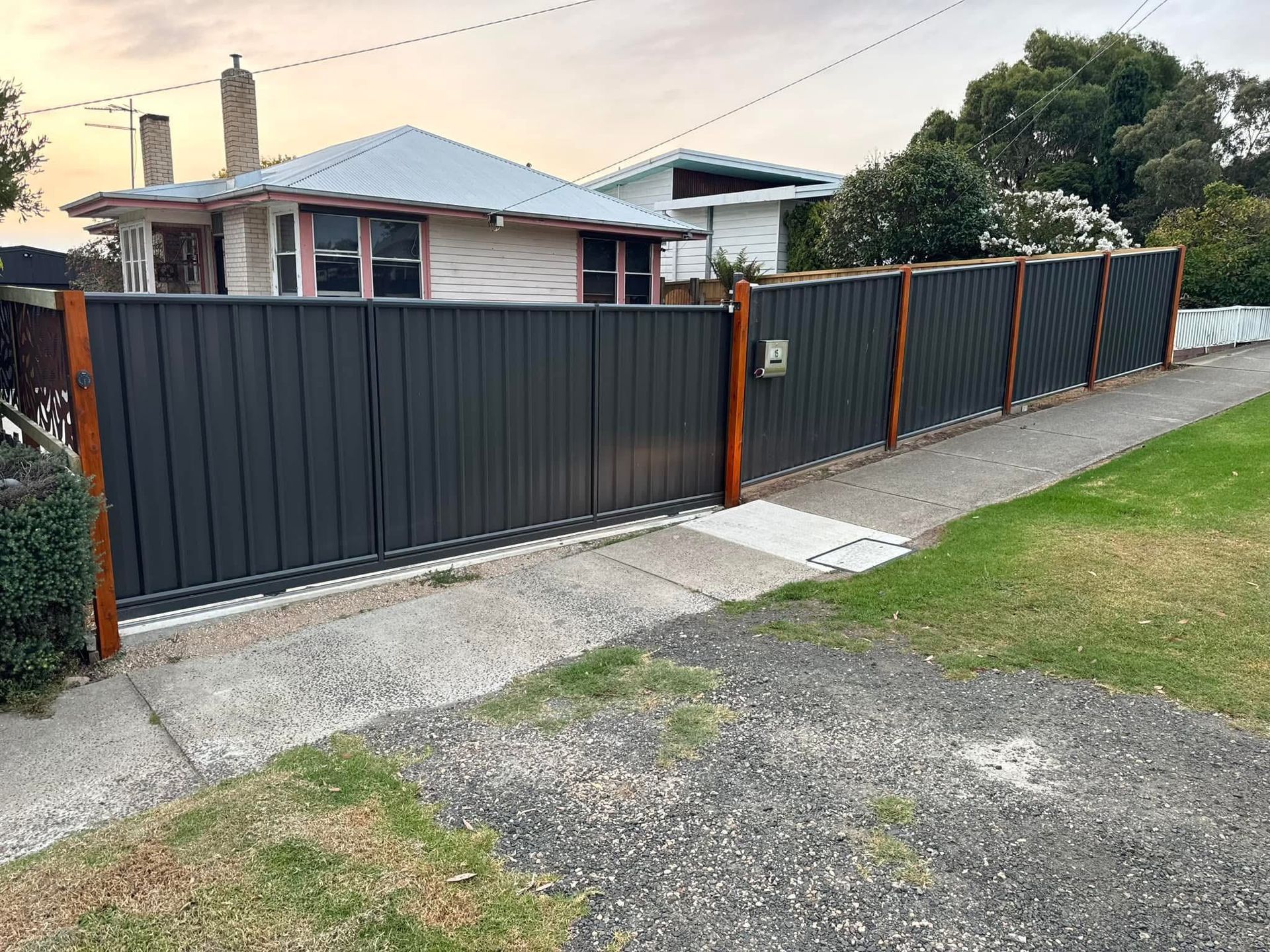 A black fence is surrounding a house on the side of the road.