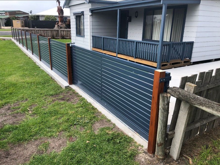 A blue fence surrounds a house with a porch.