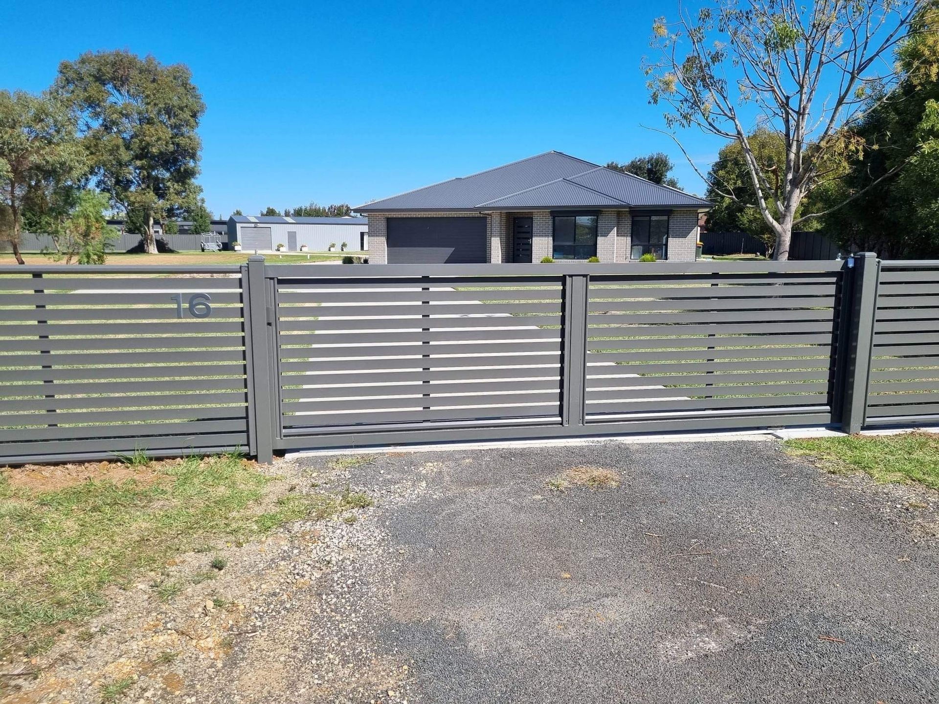 A house is behind a fence with a sliding gate