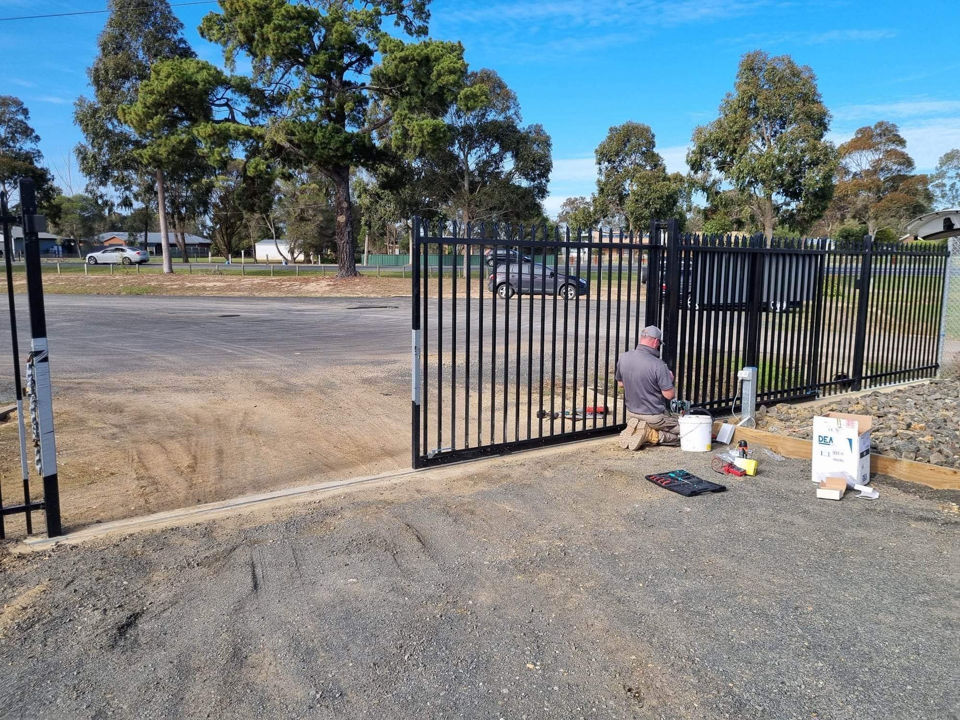 A man is painting a fence in a parking lot.