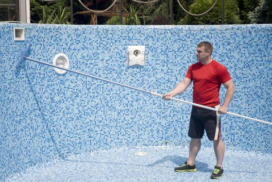 man cleaning the tiles of the pool