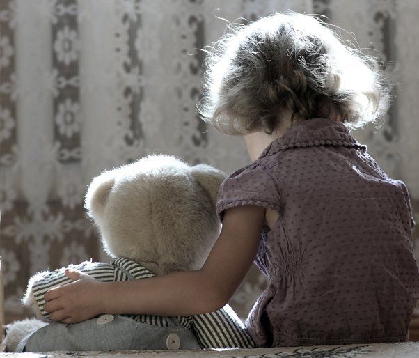 A young girl holding a teddy bear
