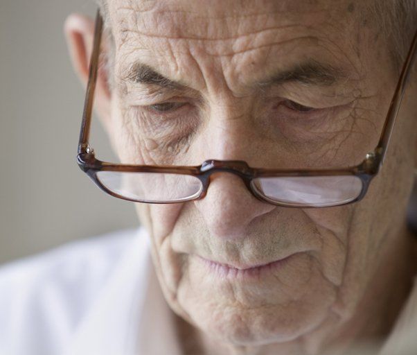 An elderly gentleman looking down through his glasses