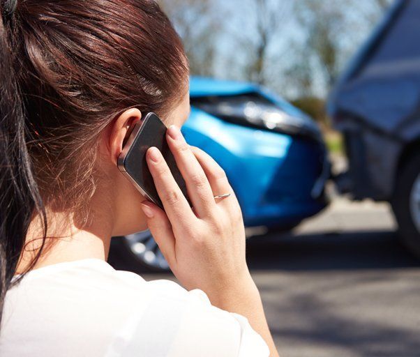 A lady on a phone with bumped cars in the background