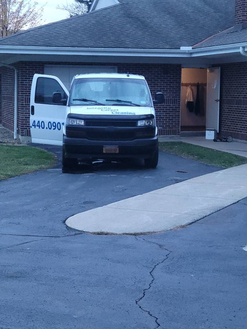 A white van with the door open is parked in front of a brick house.