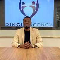 A man is sitting at a table in front of a ding agency logo.