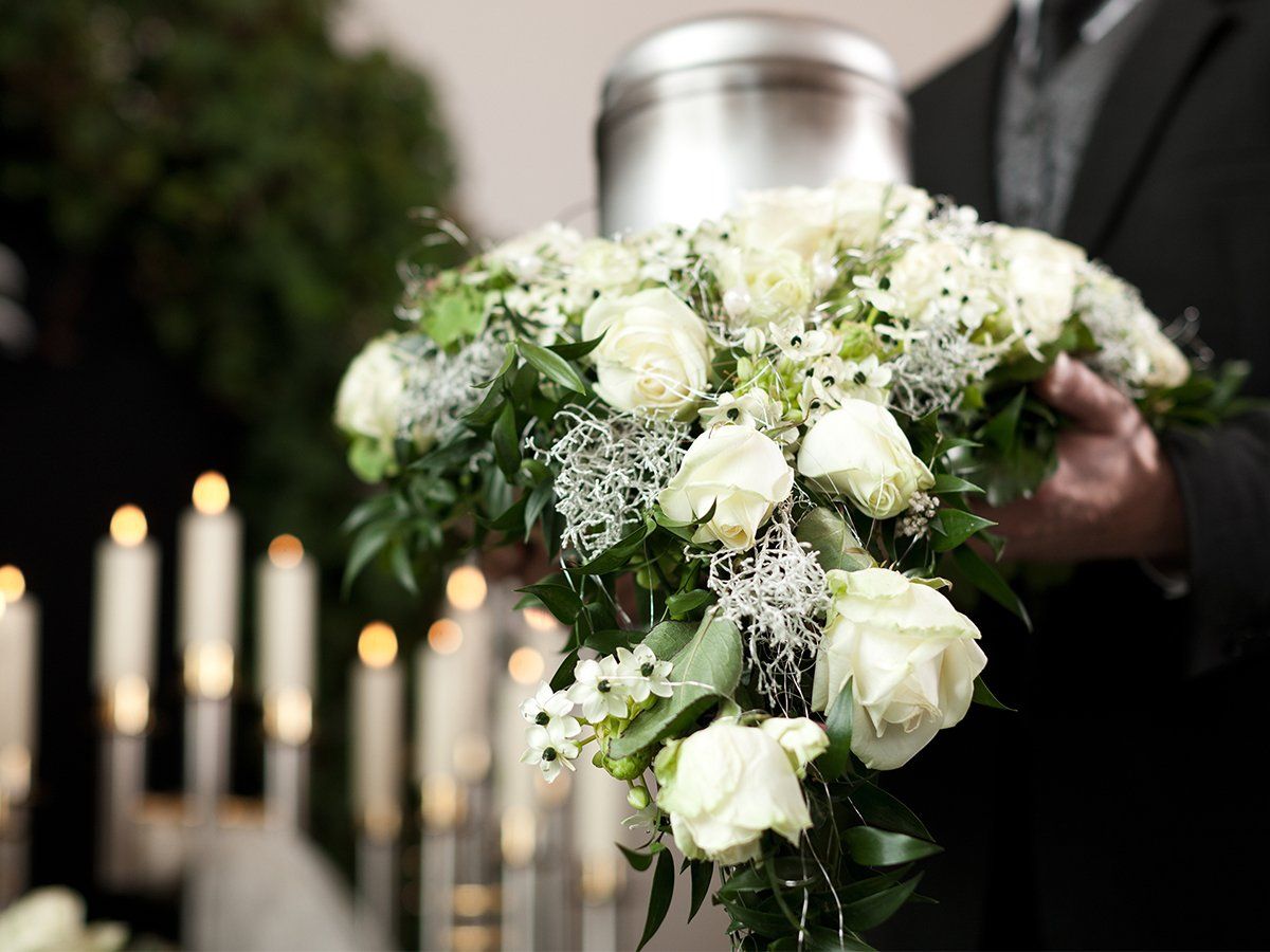 Man holding cremation urn with floral arrangement