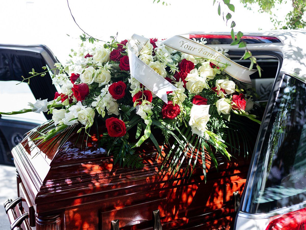 Casket in back of hearse with large flower arrangement
