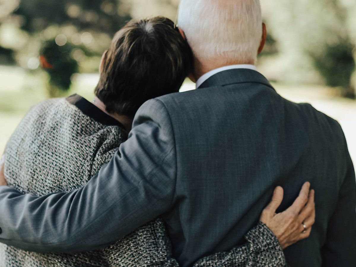 Elderly couple holding each other at a funeral
