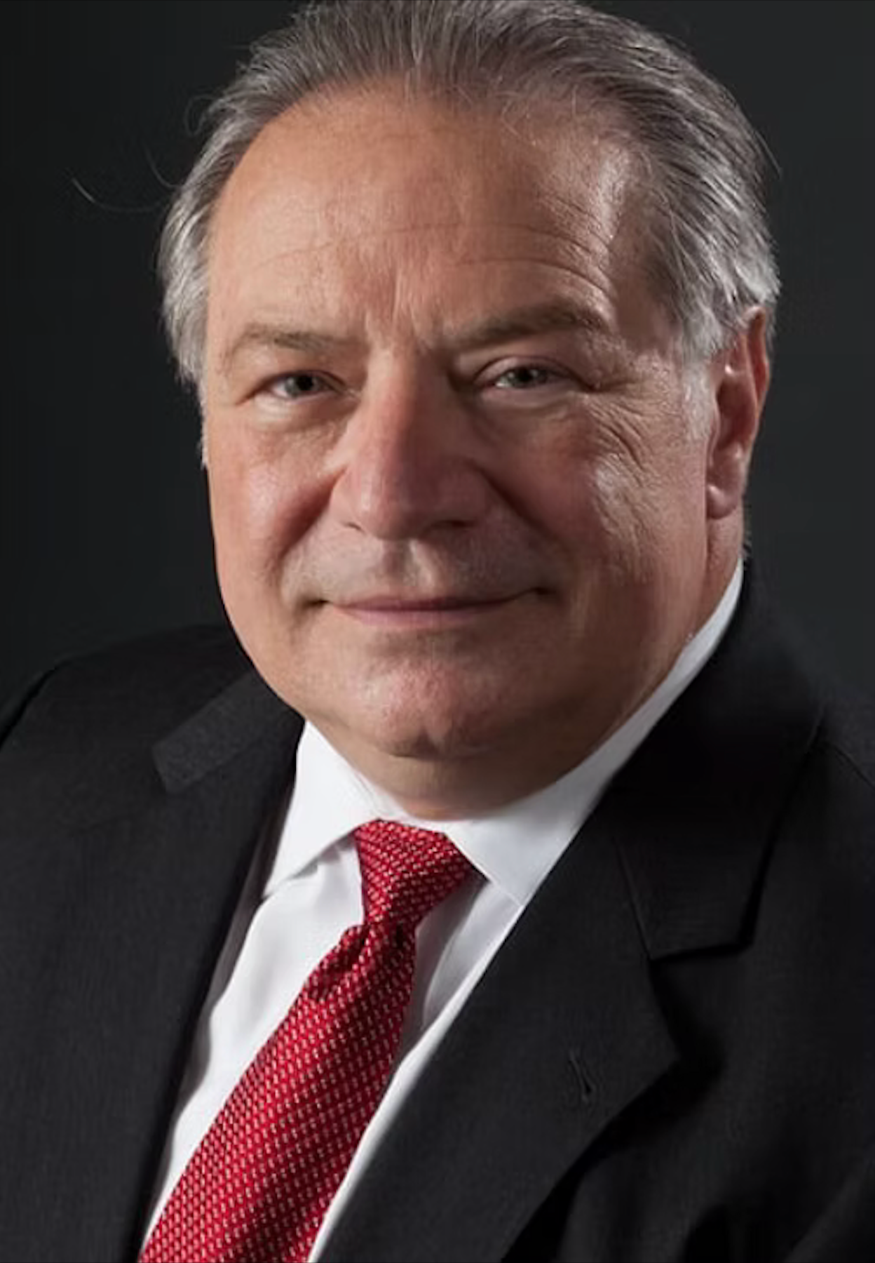A man in a suit and tie is smiling for the camera