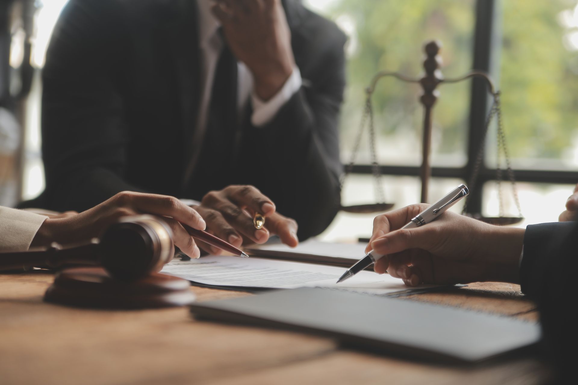 A man and a woman are sitting at a table with a gavel and scales of justice.