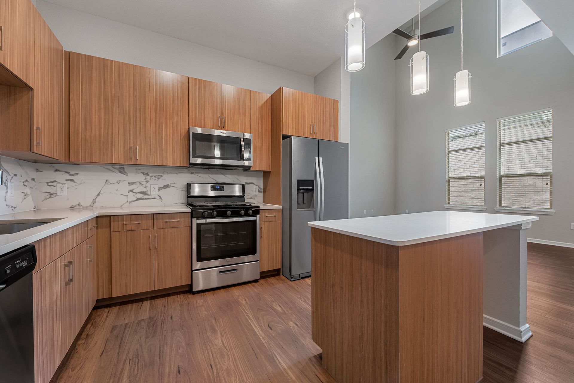 a kitchen with wooden cabinets , stainless steel appliances , and a large island at Westerly 360 in Austin, TX.