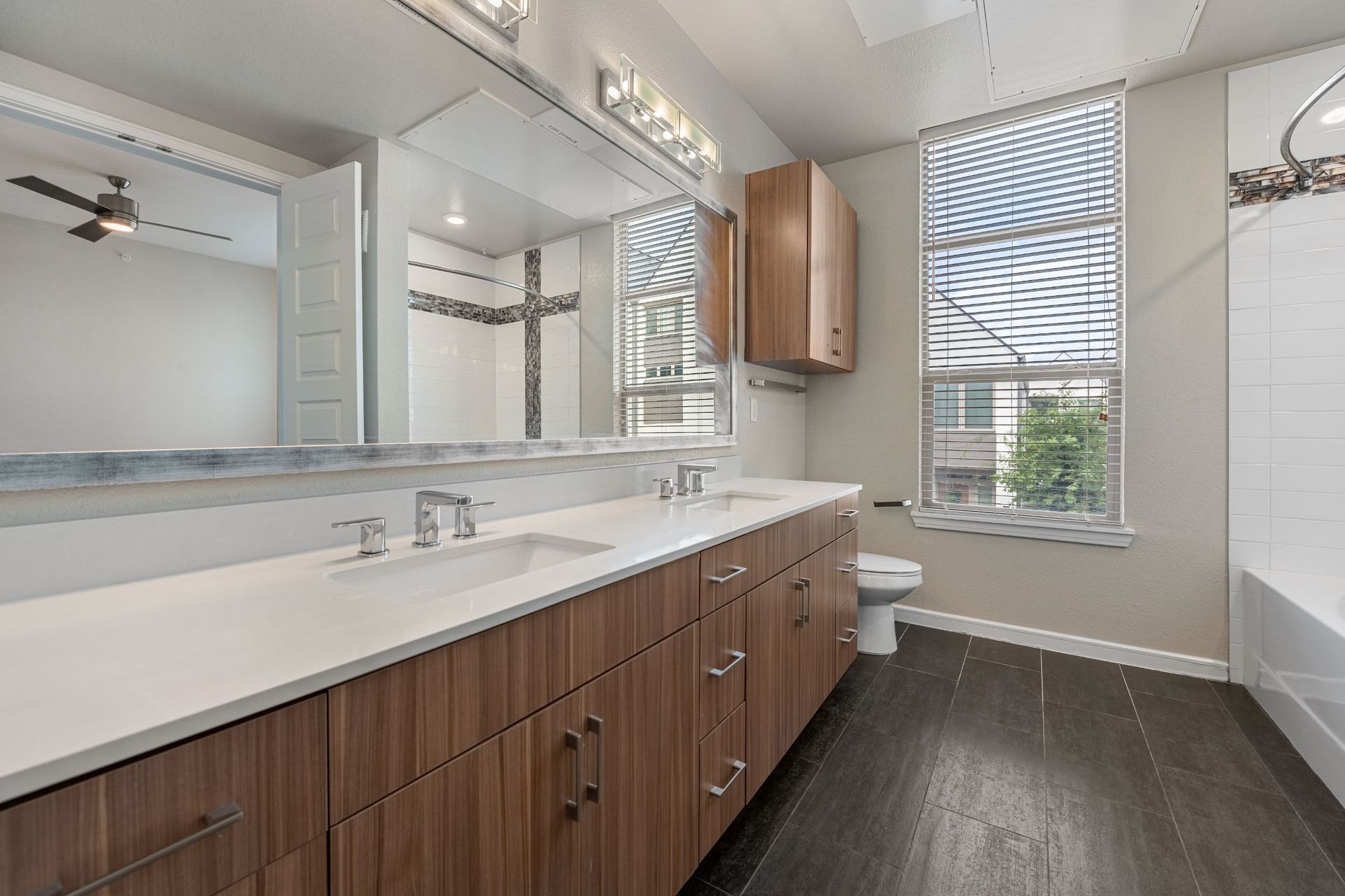 a bathroom with two sinks , a toilet , and a window at Westerly 360 in Austin, TX.
