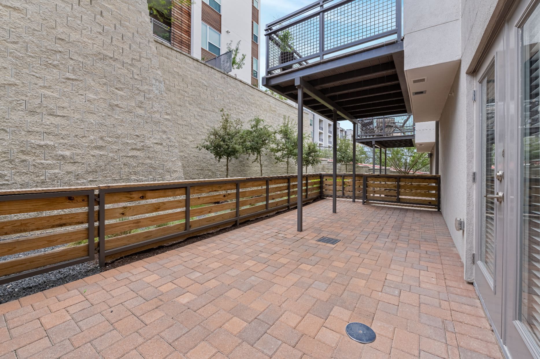a large brick patio with a wooden fence and a balcony at Westerly 360 in Austin, TX.
