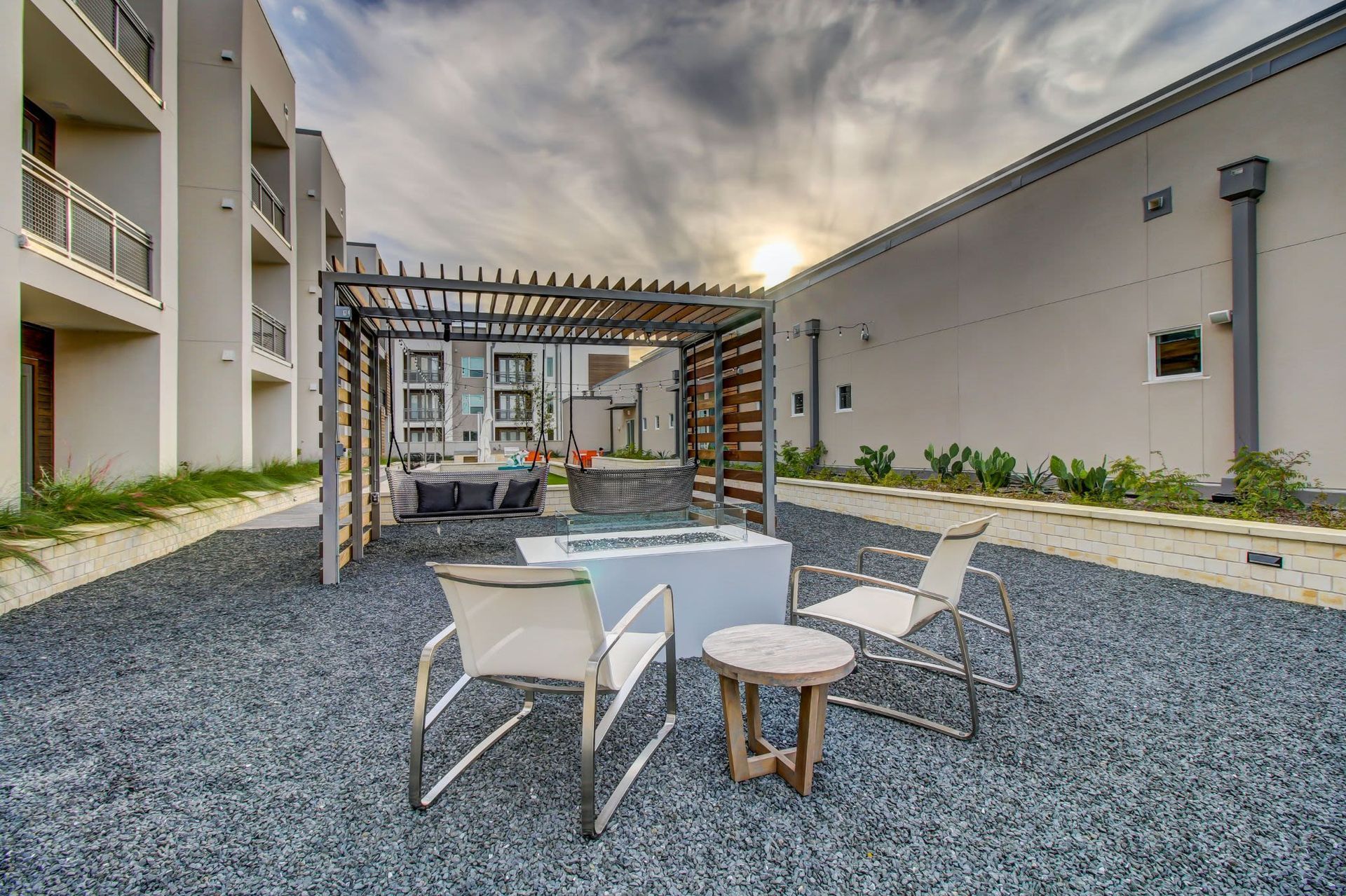 a patio area with a fire pit and chairs in front of a building at Westerly 360 in Austin, TX.