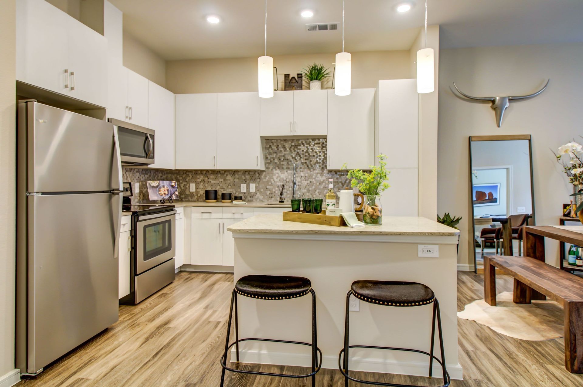 a kitchen with stainless steel appliances , white cabinets and a large island at Westerly 360 in Austin, TX.