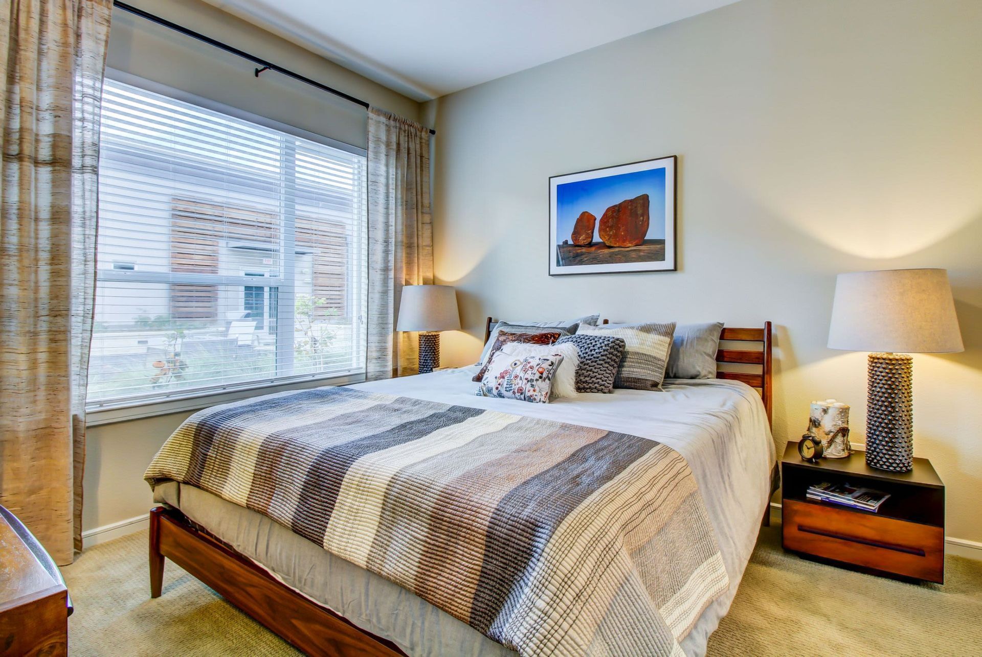 a bedroom with a bed , nightstand , lamps and a large window at Westerly 360 in Austin, TX.
