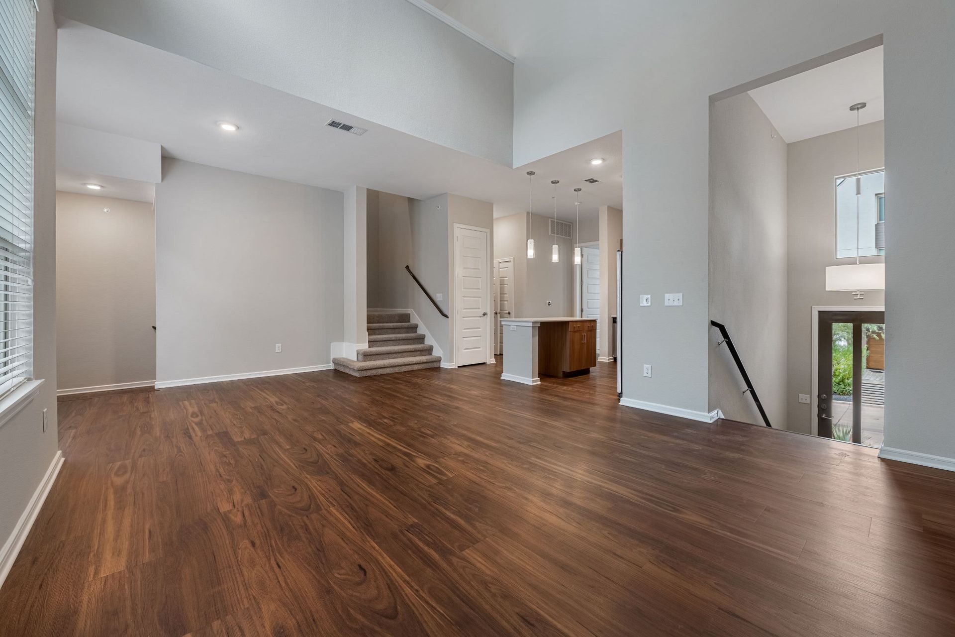 an empty living room with hardwood floors and stairs in a house at Westerly 360 in Austin, TX.