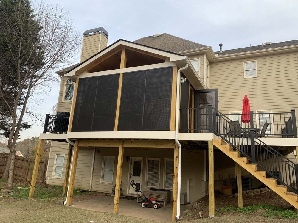 Back view of a two-story house with a screened-in porch and wooden deck.