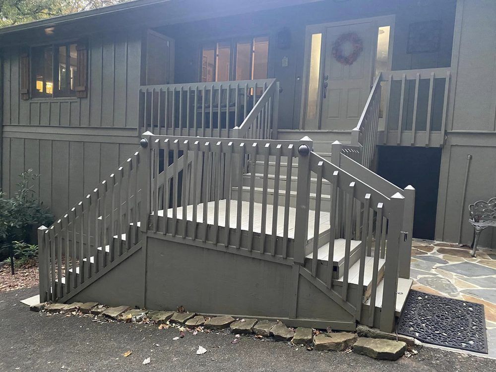 Gray house with raised entrance stairs and railings; front door has a wreath, gray siding.