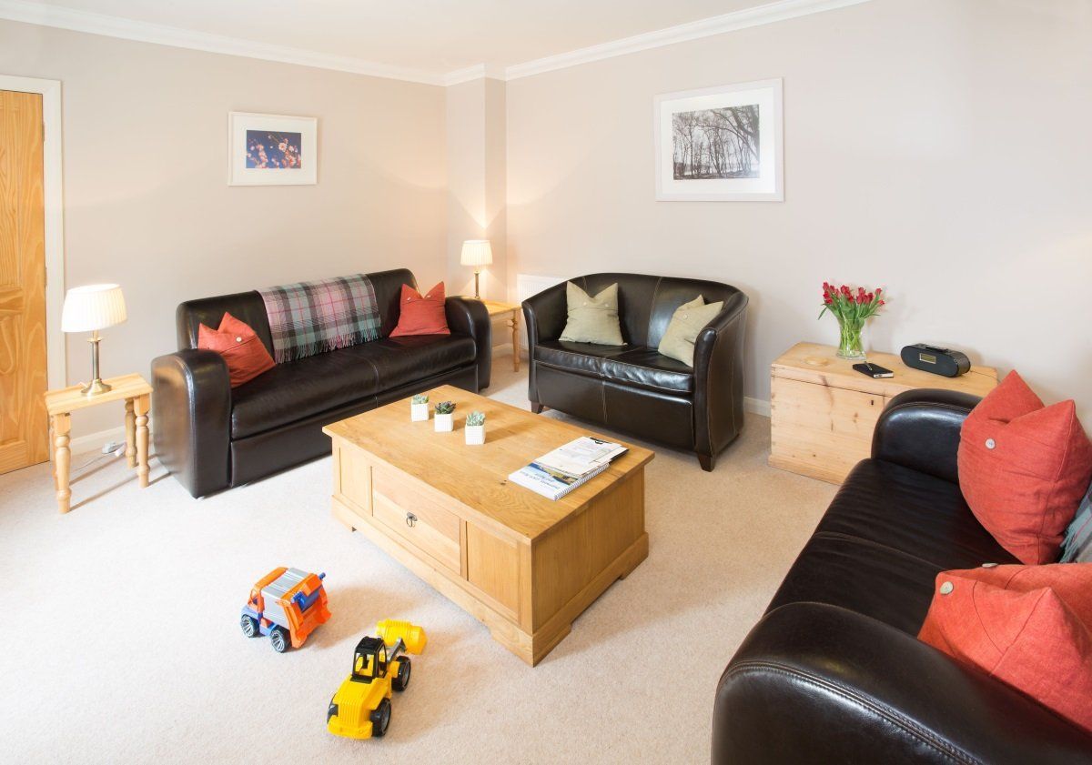 A living room with two couches , a coffee table , and toys on the floor.