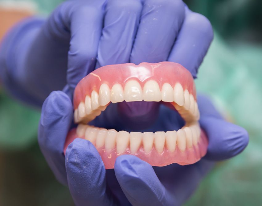 Hands With Violet Gloves Shows The Full Dentures Teeth — Smiles on Hobart In Sandy Bay TAS