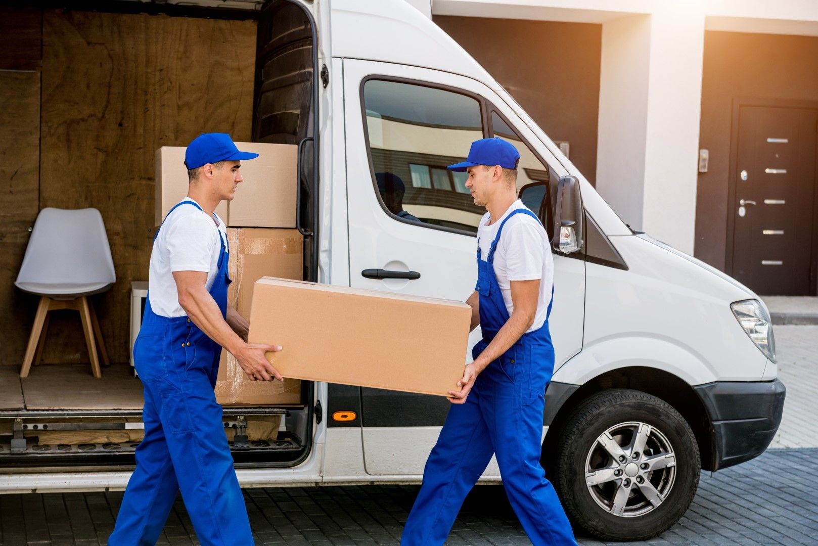 Two men are carrying boxes out of a moving van.