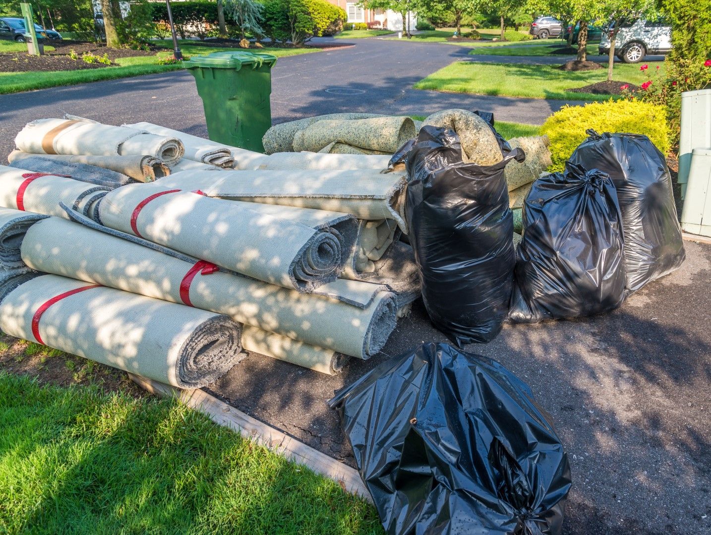 A pile of carpets and trash bags on the side of the road.