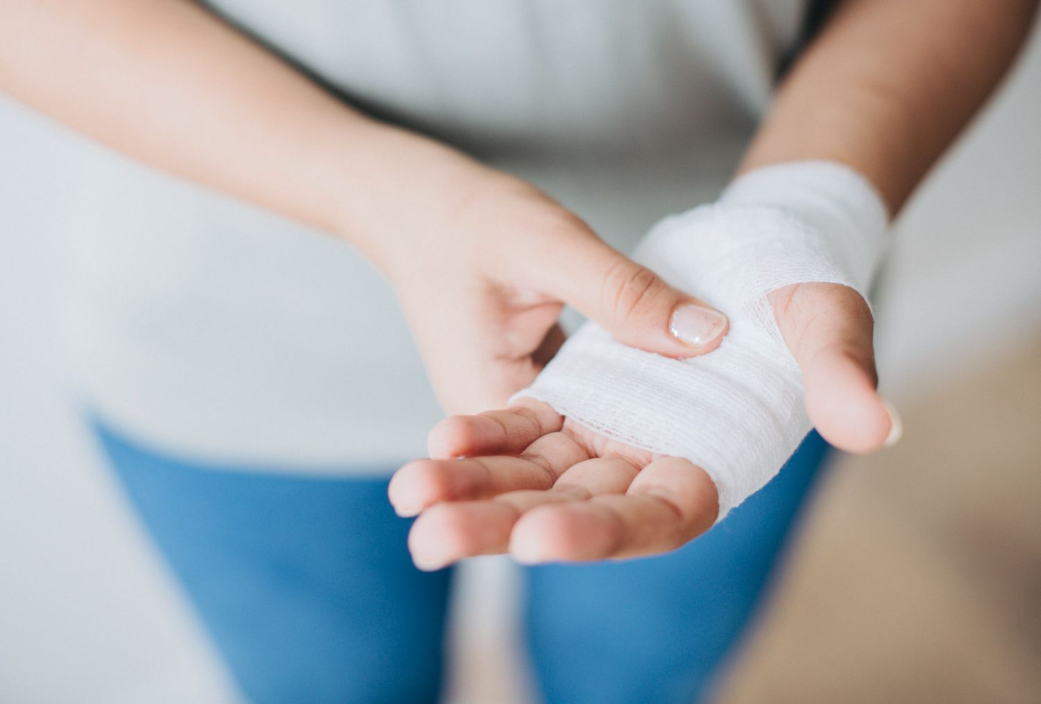 A woman is wrapping her hand in a bandage.